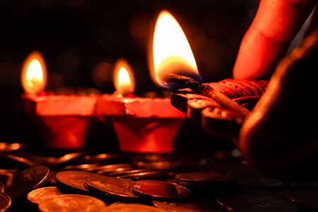 Man holding a glowing earthen lamp in hands for Deepawali decorationの写真素材