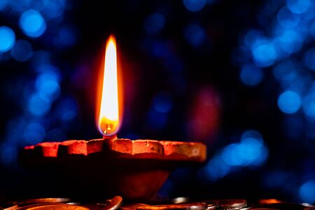 One Glowing earthen lamp on a pile of coins showing influx of money and prosperity - Lakshmi Pooja and Diwali Conceptの写真素材