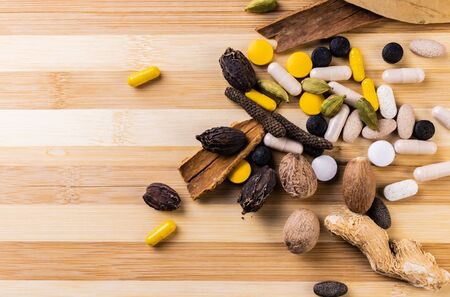 Scattered herbs and spices with ayurvedic medicines on a wooden background. Natural remedy concept