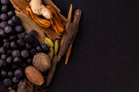 Close-up of black herbal tablets with cinnamon, cardamom, piper longum and mace on a darkの写真素材