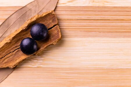 Top view macro of two black ayurvedic tablets with cinnamon sticks and bay leaves in the background...
