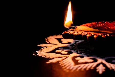 beautiful glowing terracotta lamp and white rangoli design on black background with copy space in the left. dhanteras conceptの写真素材