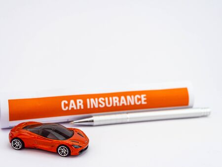 A toy car with defocused insurance paper behind and ball pen on white backgroundの写真素材