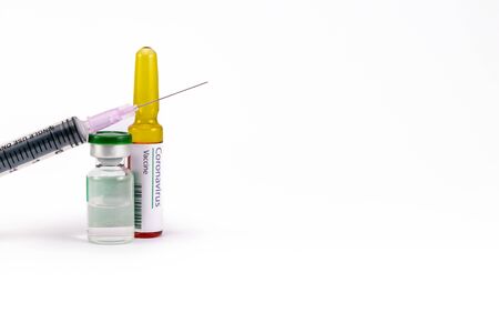An injection needle placed on a vial with one ampoule having Corona virus Vaccine labelの写真素材