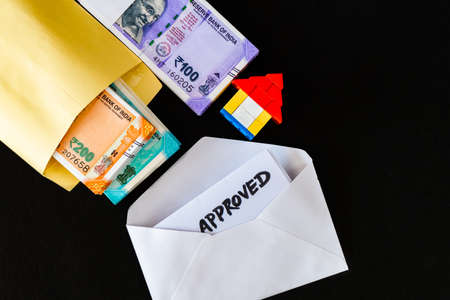 Top close up shot of house, with money packet and white envelope containing loan approvalの写真素材