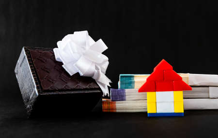 Low angle close up of a toy home, money, and gift box showing gifting house concept
