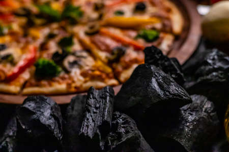 Extreme close up of charcoal and blurry pizza in the backgroundの写真素材