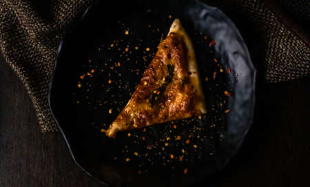 Top view of delicious slice Margherita Pizza with superadded chilli, pepper on black plateの写真素材