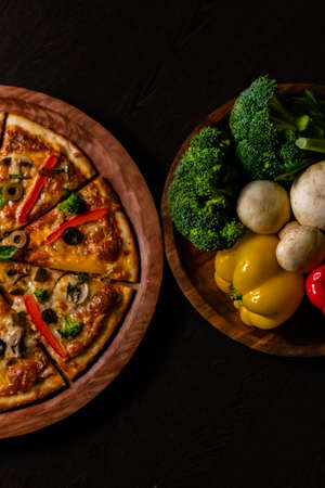 Portrait Photography of delicious Picante pizza with colourful vegetables kept on black surface.の写真素材