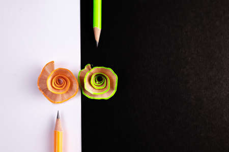 Two pencils and their shavings over black & white background having copy space on right