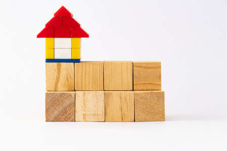 Eight wooden blocks in two rows above each other and a  house on top for bank loan conceptの写真素材