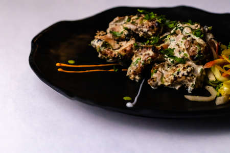 Delicious Chicken Malai Tikka with colorful veggies on white surfaceの写真素材