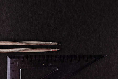 A divider with its pointed legs in the direction of a set square shot from the top -geometry concept