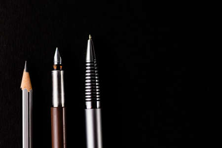 Top close up shot of two pens and a pencil over black backgroun in Education concept