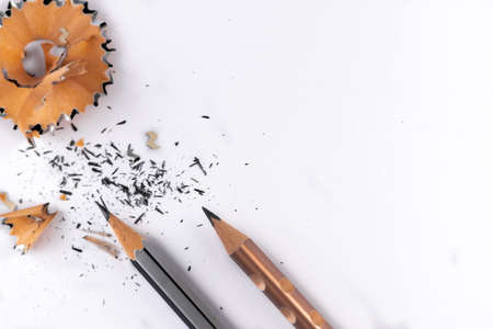 High angle close up of two pencils with sharpener waste and broken graphite pieces on white paperの写真素材
