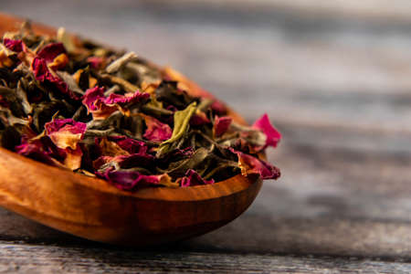 Close up shot of dry rose petals on wooden spoon with defocused backgroundの写真素材