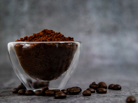 Coffee powder in glass bowl with beans scattered below.の写真素材