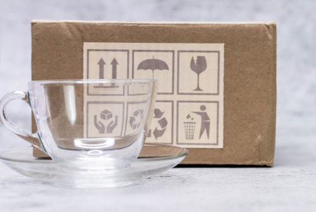 Close shot of glass cup with defocused fragile box in the background and copy space.