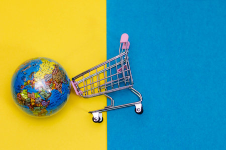 Top shot of cart with globe placed on blue and yellow background.