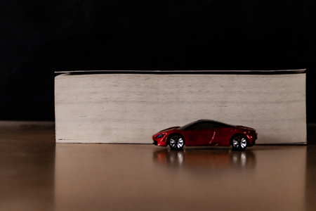 Front close up shot of a red toy car with a thick book in focus behind it - Rich Lifestyle concept.
