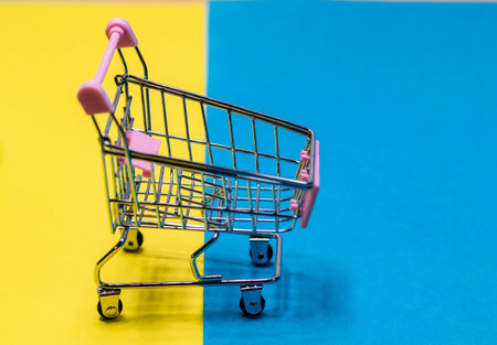 High angle shot of empty cart placed on yellow and blue background.の写真素材