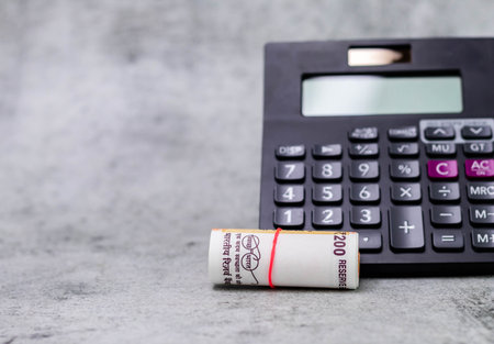 Close up shot of rolled money with calculator on the background and copy space.の写真素材