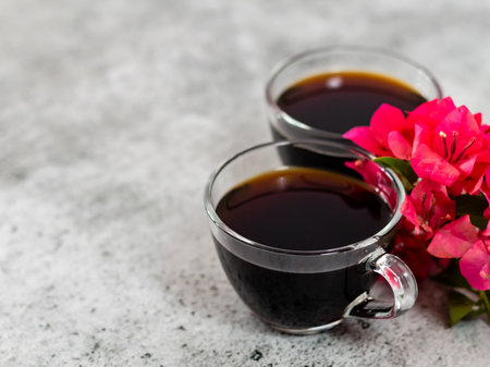 High angle shot of black coffee cups with pink flowers and copy space on the side.の写真素材