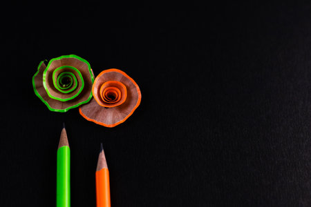 Two pencils and colorful shavings shot using prime lens against black background.の写真素材
