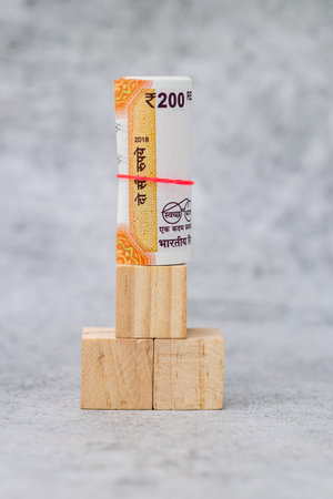 Close-up shot of rolled money placed on wooden cubes in portrait orientation - shipping concept.の写真素材