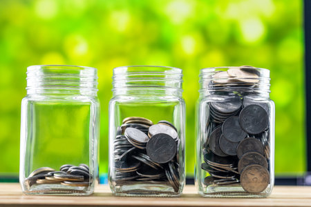 Three glass jars containing coins - money-saving concept.の写真素材