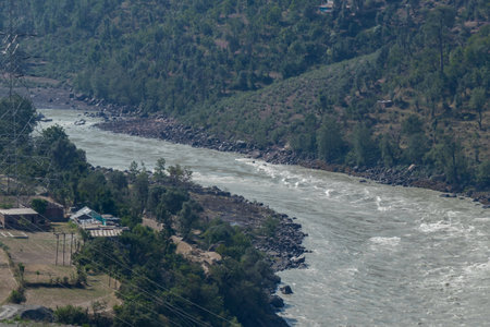 Small houses on the bank of a river flowing through the mountains.