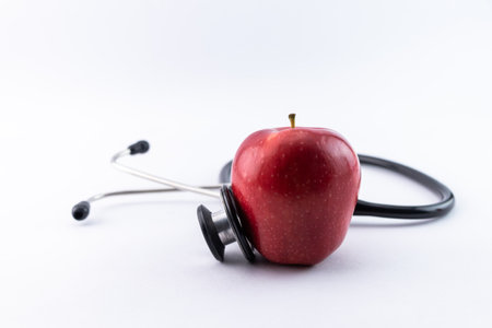 Apple and stethoscope on a white background. Healthy eating. Good health concept.