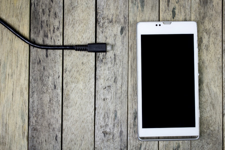 smart phone need to charge a battery on wood plank, top view, close-upの写真素材