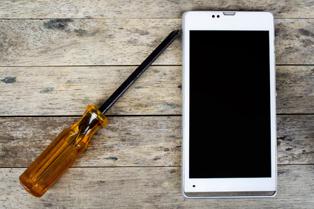 smart phone and screwdriver for repair on wood plank,  top view, black screenの写真素材