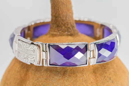 Close up, old silver bangle with an amethyst, set on mahogany seed background.Handmadeの写真素材