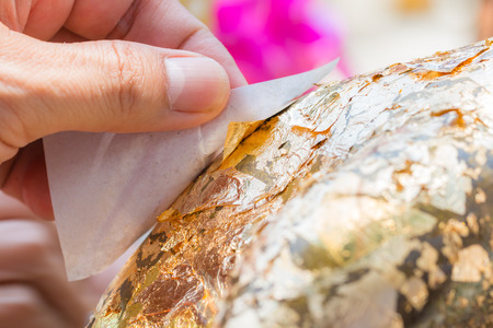 Gilding Buddha, Hand was pressing a sheet of gold leaf on Buddha, the tradition of Buddhist in Thailand.の写真素材
