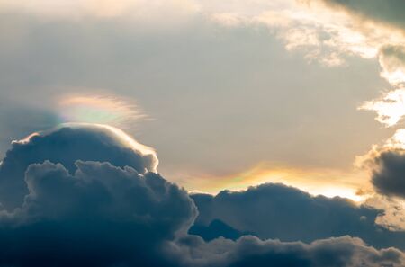 Abstract background, scenery of dramatic sky in evening, with storm clouds and spectrum, blue, grey, orange, golden light in twilight, looks like watercolor painting.の写真素材
