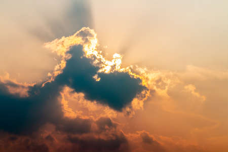 Abstract background of colorful dramatic sky in evening, with dark cumulonimbus and sunlight breaking through clouds, in soft blurred style, blue, grey, orange, golden light in twilight.の写真素材