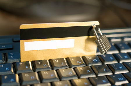 Credit card with hanging padlock on keyboardの写真素材