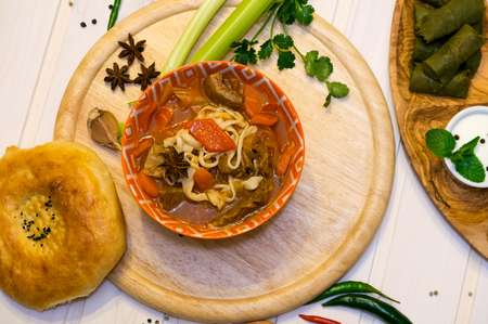 Traditional soup lagman with flatbread on wooden boardの写真素材