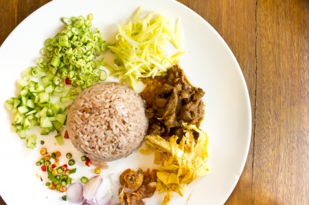 A dish of rice mixed with shrimp paste serve with omlet, pork and various vegetable の写真素材