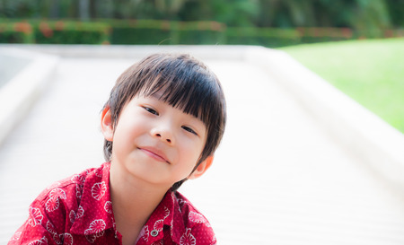 Close up portrait of cute boy smiling in the parkの写真素材