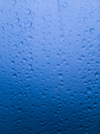 The water drops on glass in blue tone background