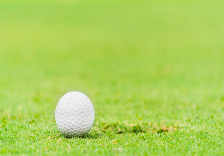 A golf ball near the lip of cupの写真素材