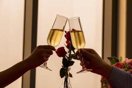 close up silhouette couple hand toasting champagne glass celebrating on Anniversary, New Year, birthday or Valentine. back to normal lifestyle. dinner dating together at home. banner with copy spaceの写真素材