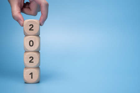 hand putting wooden block on stack of 2021. advertisement use for Happy New Year, education or...