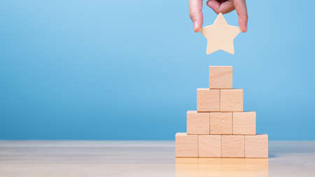 Banner of hand putting star on pyramid of stack wooden block. concept for reward, business, success...