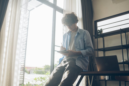 Businessman or creative freelancer writing on digital tablet. Man study online and note on the device at home. People connecting with technology working remotelyの写真素材