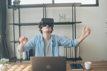 Creative designer excited watching on VR glasses headset. Man having virtual reality experience. Touching air while playing video game or simulation worldの写真素材
