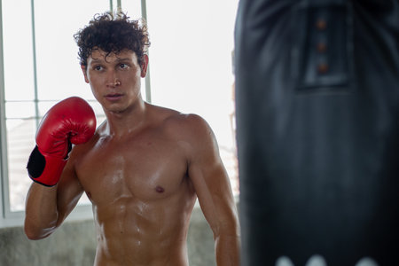 Portrait of young Caucasian muscular strong man in boxing gloves training exercise in gym fitness. Boxer workout punching bag fist. fighting sportの写真素材